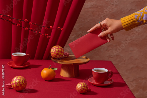 A festive still life of a hand with a red envelope with tea cups