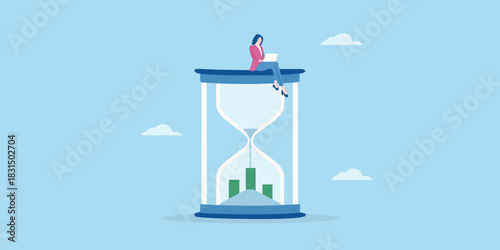 Businesswoman working on laptop atop hourglass with financial graph inside