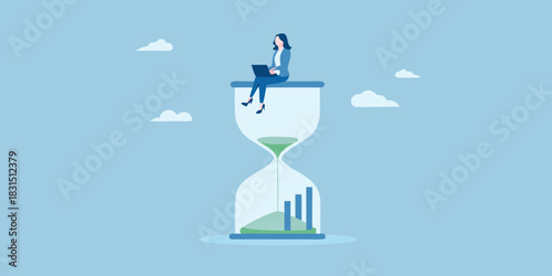 Businesswoman working on a laptop on top of an hourglass