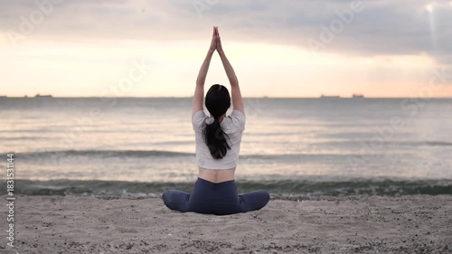 夕方の海辺でヨガをする女性の後ろ姿
