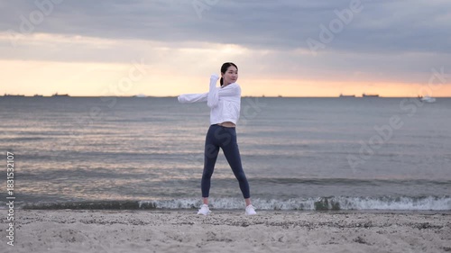 夕方の海辺でストレッチをする女性