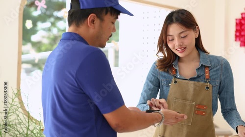 Courier and female small business entrepreneur verifying package via mobile device inside coffee shop, representing modern cashless payment, delivery service reliability, collaboration online orders