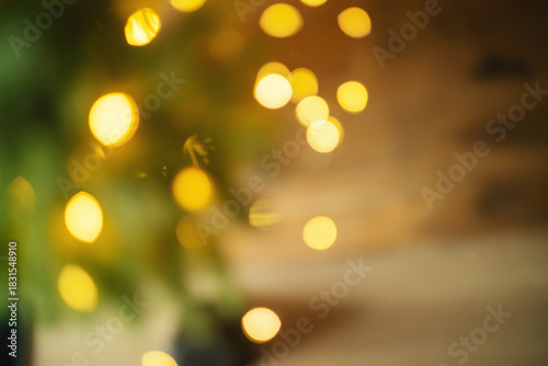 Festive golden bokeh among fir branches, warm Christmas background. High quality photo