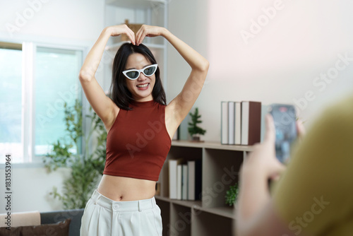 Social Media Fun. Young woman making a heart shape while posing for a video.