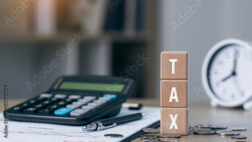 Wooden blocks showing tax 2026 on blue background. income tax form, coins, and financial documents on wooden desk, symbolizing budgeting, filing, and fiscal strategy