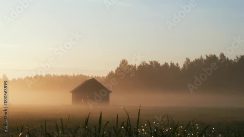 Misty sunrise over a field with a silhouetted barn.