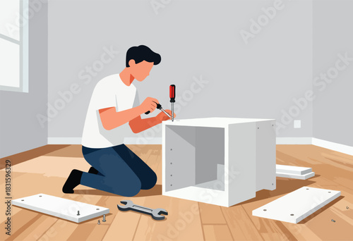 A man assembles a white cabinet on a wooden floor, using a screwdriver, with parts scattered around