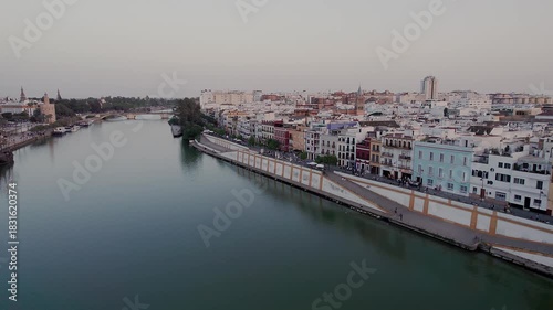 Wallpaper Mural Guadalquivir River separating Triana district on left from Paseo de Cristóbal Colón embankment on right, with Torre del Oro and Puente de Triana in background of Seville cityscape, low aerial, Spain Torontodigital.ca