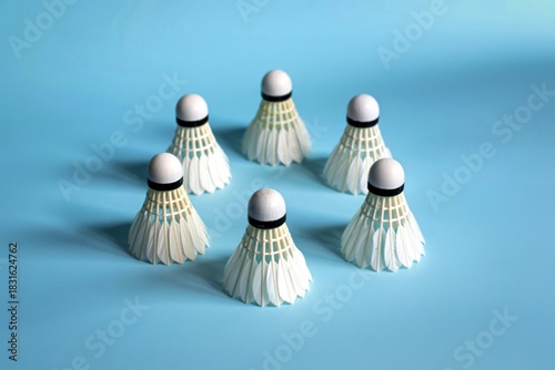 Six white badminton shuttlecocks arranged in a circle on a blue background