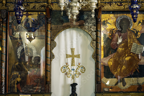 Photos Iconostasis in Mykonos, Greece, featuring a white curtain with a gold cross and ornate floral designs at the center