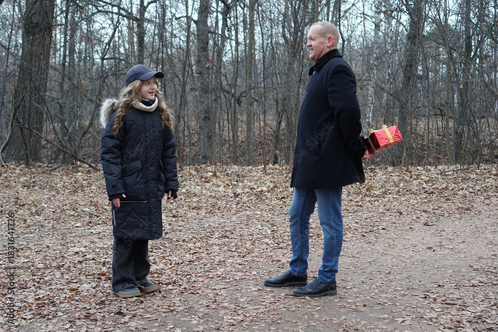 Fototapeta premium Father surprising daughter with a hidden gift in an autumn forest