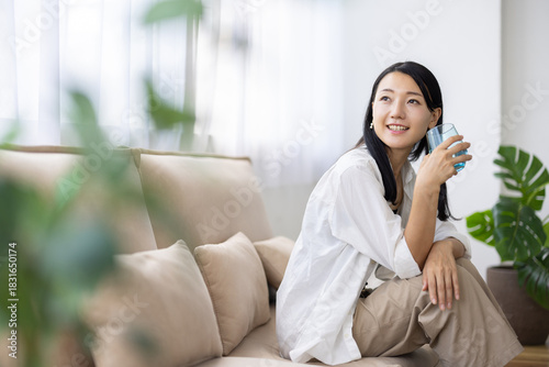Smiling Woman Holding a Glass of Water in Bright Living Room