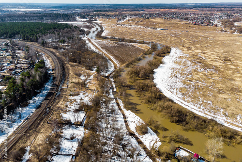 Fotografie Aerial view captures the muddy spring river swollen from snowmelt flowing past r