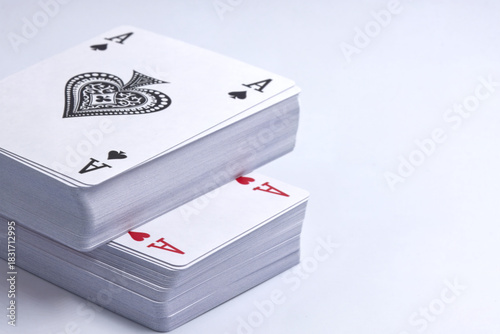 Two decks of playing cards stacked on a white background, with the Ace of Hearts and the Ace of Spades on top.