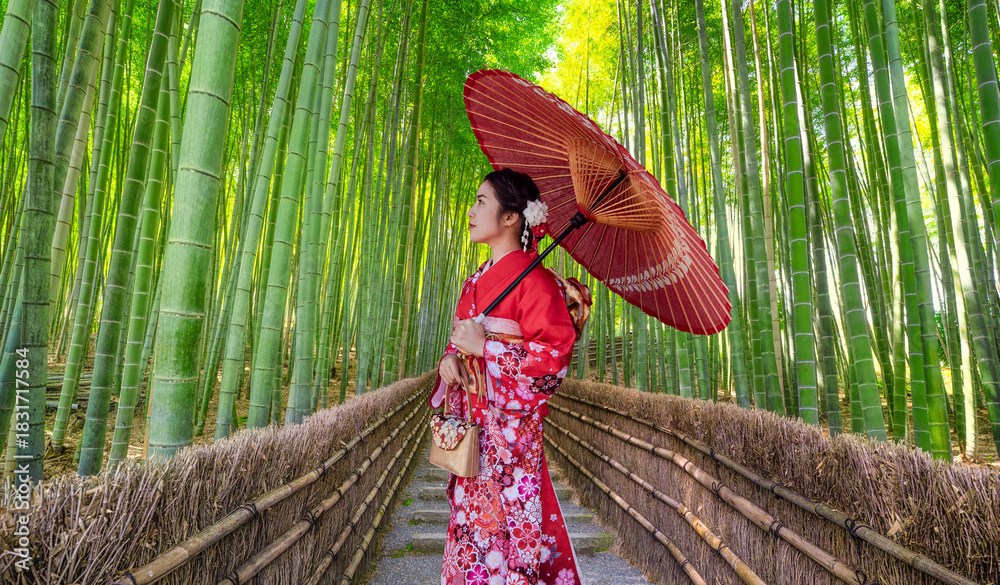 Fototapeta premium Bamboo forest. Japanese girl wearing a traditional Japanese kimono at the bamboo forest in Kyoto, Japan.