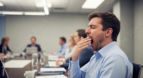 Man yawning in a meeting room, looking bored and tired.