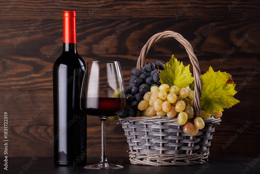 Fototapeta premium Red wine bottle with a glass and basket of fresh grapes