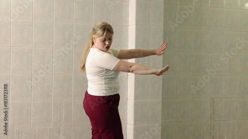 swim coach, swim mentoring, technique demonstration. Woman swimming coach demonstrates freestyle arm motion on land, teaching proper swim technique in indoor pool environment.