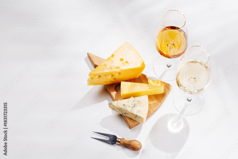 Fototapeta premium Assorted cheeses and wine glasses on white background