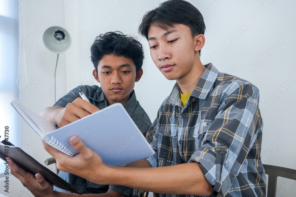 Obraz premium Two Young Asian Men Collaborating On Homework, Sharing Ideas And Studying Together
