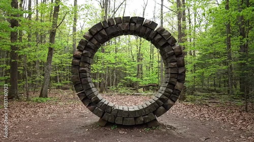 Circular wooden archway installation in a vibrant green forest setting