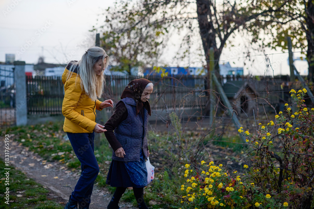 Obraz premium Middle-aged woman visits her elderly mother and walks through the garden