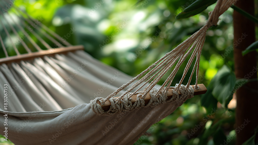 Fototapeta premium Close-up detail of a white cotton hammock hanging in a lush green garden inviting relaxation and leisure.