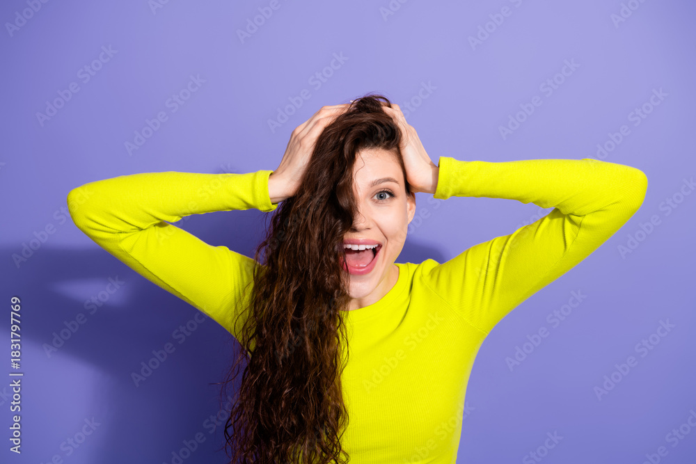 Fototapeta premium Young woman with neon yellow top smiles playfully against a purple background showcasing fashion style confidence and joyful lifestyle photography