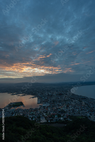 Dramatic sunset clouds and golden light illuminating the iconic cityscape of Hakodate, Hokkaido, viewed from Mount Hakodate.