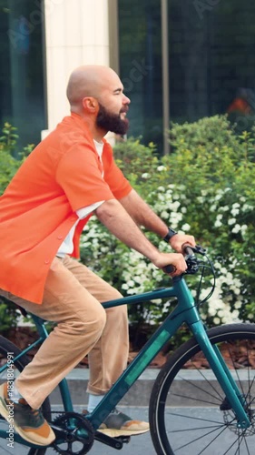 Focused bearded man riding bicycle in helmet at business district. City mobility. Confident businessman using rental city transport.