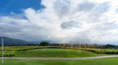 Landscape of green grass Lawn yard, golf couse with a concrete walkway on lawn land, mountain in background under cloudy sky