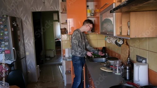 young man in the kitchen is preparing food for himself