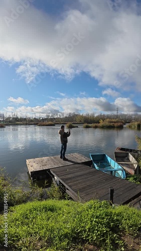 Man Filming with Smartphone from a Small River Dock