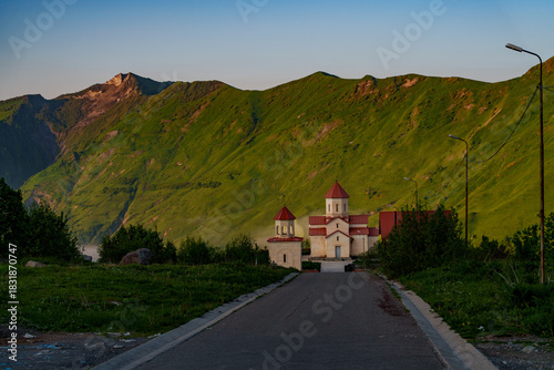 Mountain road leading to Georgian church at golden hour
