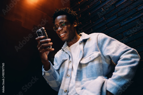 Young man momentarily raising his smartphone, perhaps capturing a selfie or recording video, symbolizing self‑expression and mobile technology’s role in modern personal storytelling.