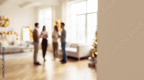 Blurred photo of a group of friends standing in a living room with New Year decor and large windows