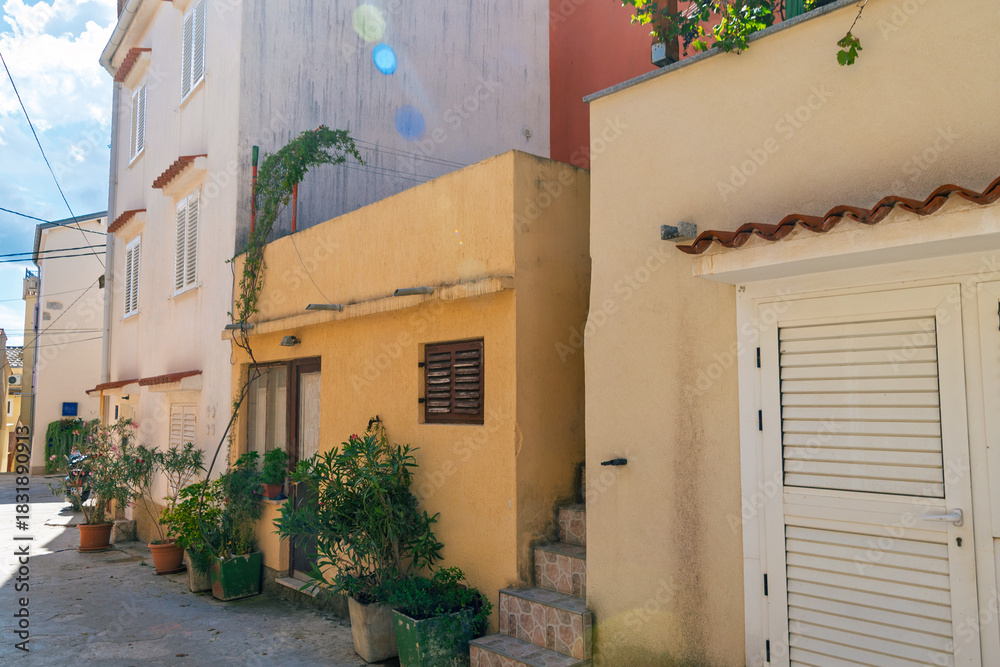 Obraz premium Charming mediterranean street with colorful houses and lush greenery. Omišalj, Krk island, Croatia