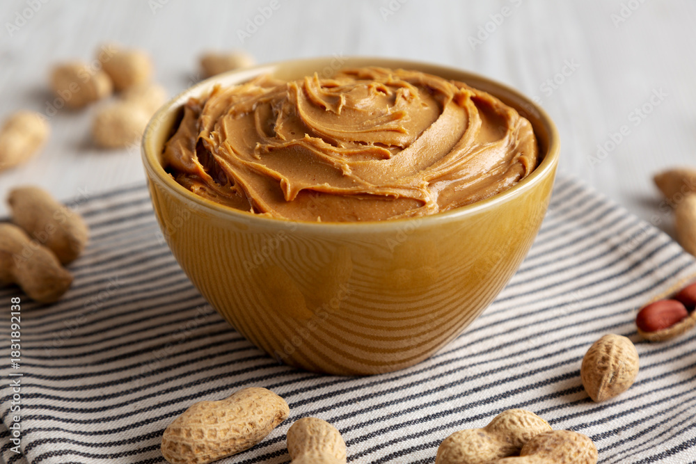 Fototapeta premium Creamy Brown Peanut Butter in a Bowl, low angle view. Close-up.