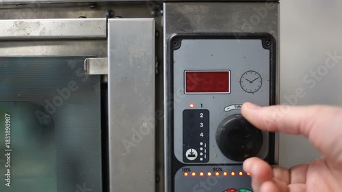 The chef starts the timer on the combi-steamer. Professional kitchen.