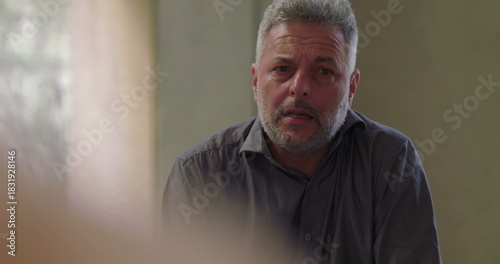 Φωτογραφία Man speaks with emotion during therapy session, seated in circle with focused ga