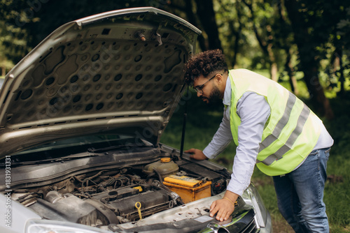 Canvas Print Man wearing safety vest checking broken car engine