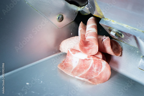 Thinly sliced raw pink meat (pork or beef) rolled up, freshly cut by a meat slicer machine, ready for hot pot or shabu-shabu.