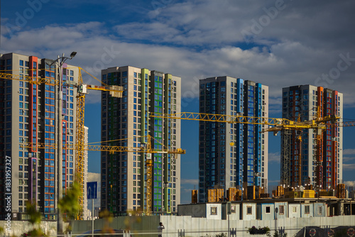 Construction cranes and new buildings, construction work of modern skyscrapers on a sunny day.