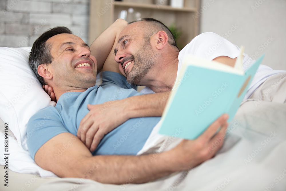 Obraz premium happy gay couple lying on bed at home