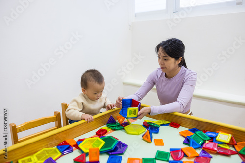 Mother playing with her baby in playhouse using magnet tiles