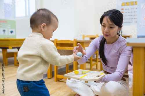 Happy mother and baby playing together at playhouse