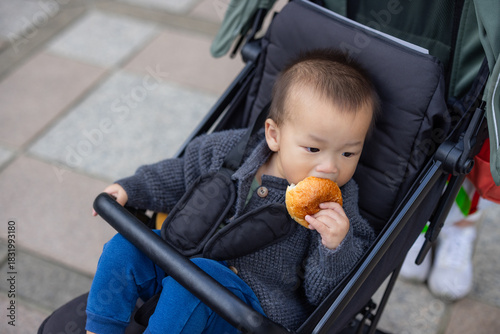 Little baby enjoying snack while sitting on stroller