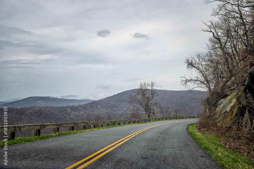 Fototapeta premium Car pov point of view driving on winding road in Blue Ridge mountains parkway in Virginia with paved asphalt road and cloudy overcast sky