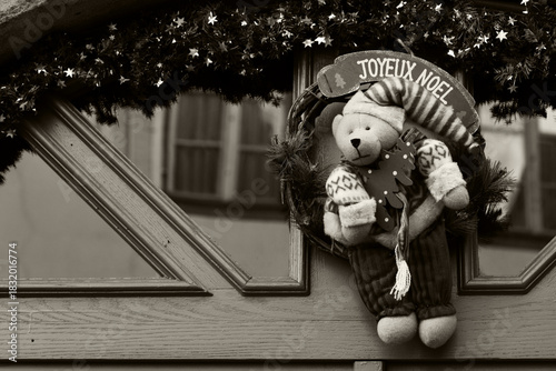 Alsace, France. Christmas wreath decoration on house door with teddy bear holding Christmas tree. 