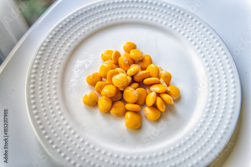 Lupini beans snack on white plate background macro closeup, healthy Mediterranean food appetizer